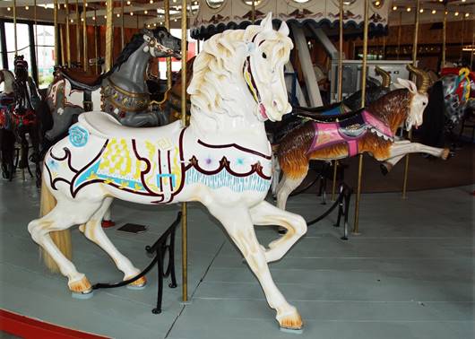 A carousel horse with horses on a merry go round

Description automatically generated