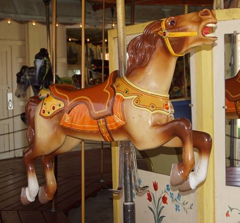 A horse statue in front of a carousel

Description automatically generated