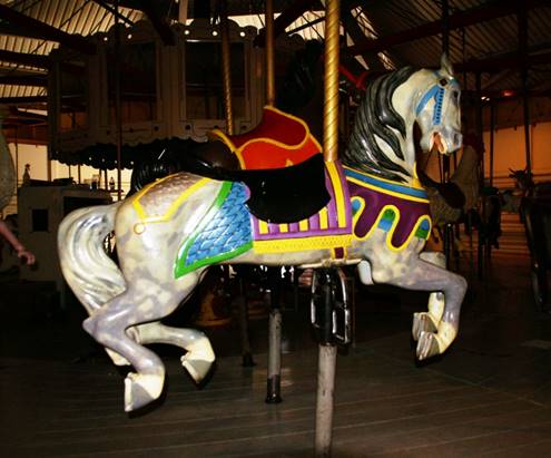 A person riding a horse in a carousel

Description automatically generated