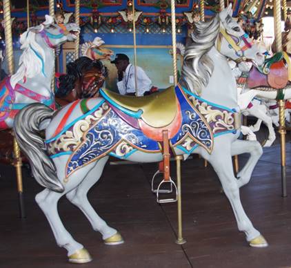 A group of people standing in front of a carousel

Description automatically generated