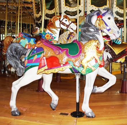 A group of people standing in front of a carousel

Description automatically generated