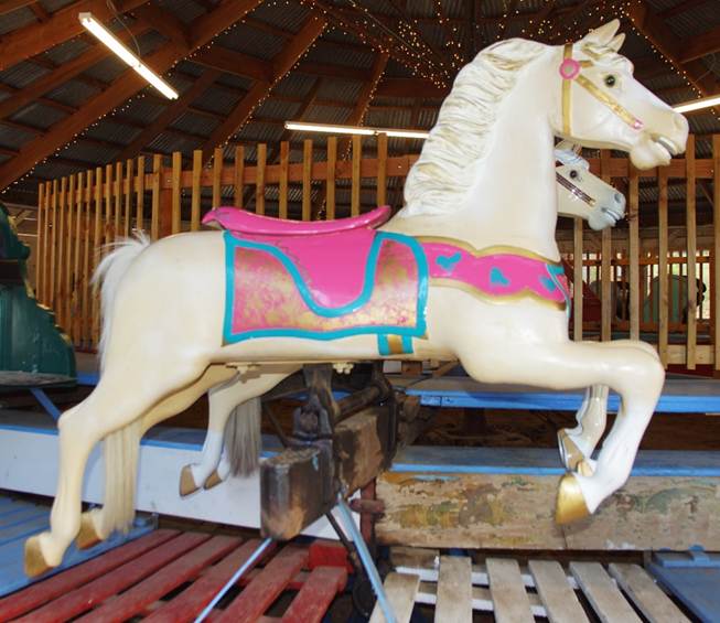 A horse statue in front of a carousel

Description automatically generated